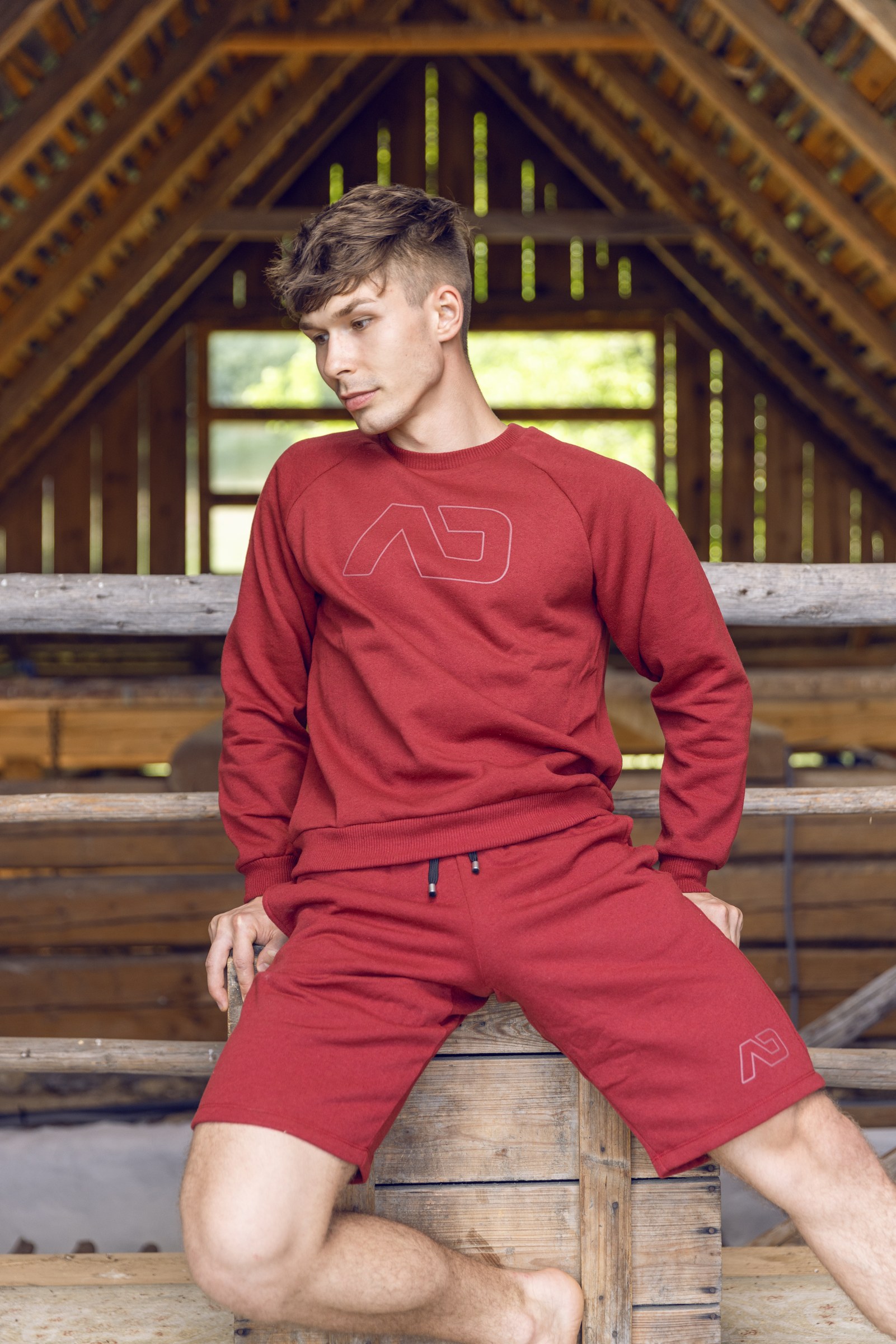 BelAmi-modell piros ADDICTED melegítőszettben egy fából ácsolt pajtában